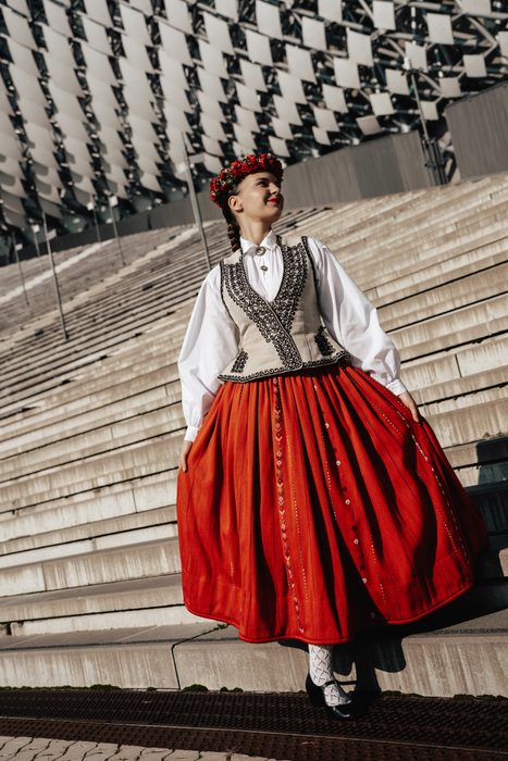 Māsa tautastērpā ar sarkanu vainagu un svārkiem uz Mežaparka estrādes kāpnēm