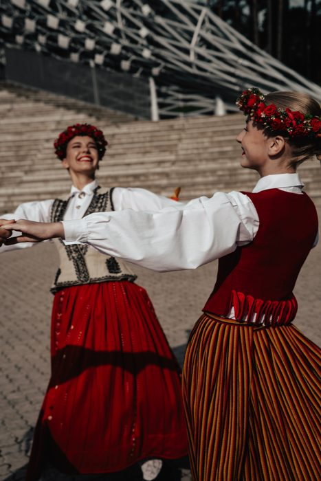 Divas māsas tautastērpos dejo sadevušās rokās pie Mežaparka estrādes