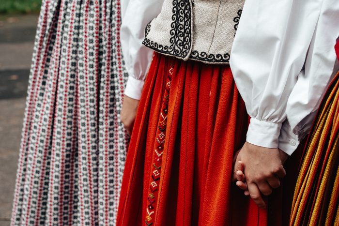 Tautastērpu svārku un sadevušos roku tuvplāns Mežaparka fotosesijā