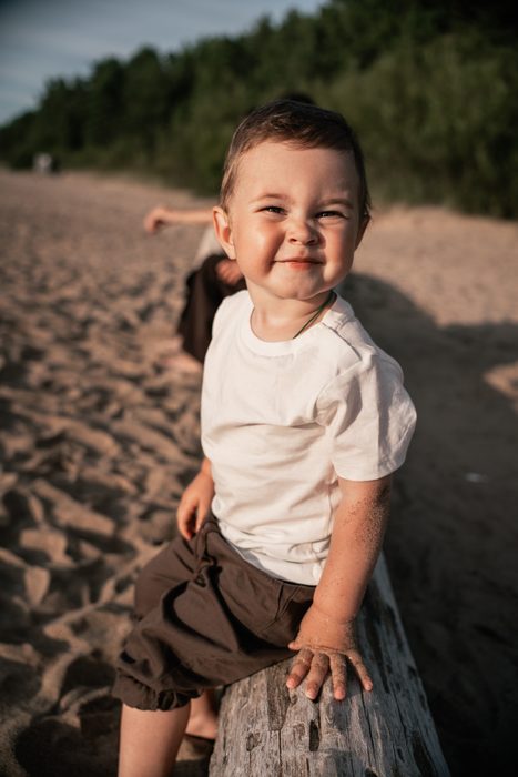 Mazs bērns smaida smilšainā pludmalē