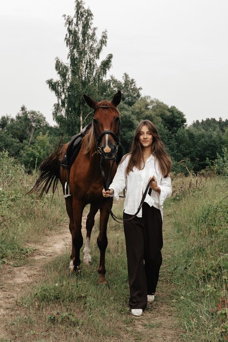 Woman in a white shirt with a horse in a field