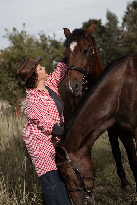 Woman in a pink checked shirt beside a horse