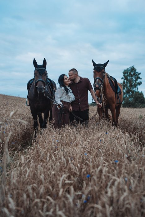 Pāra fotosesija ar diviem zirgiem labības laukā