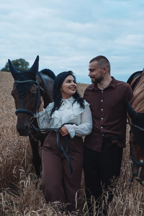 Pāra fotosesija ar diviem zirgiem labības laukā