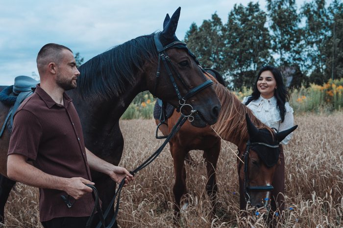 Pāra fotosesija ar diviem zirgiem labības laukā