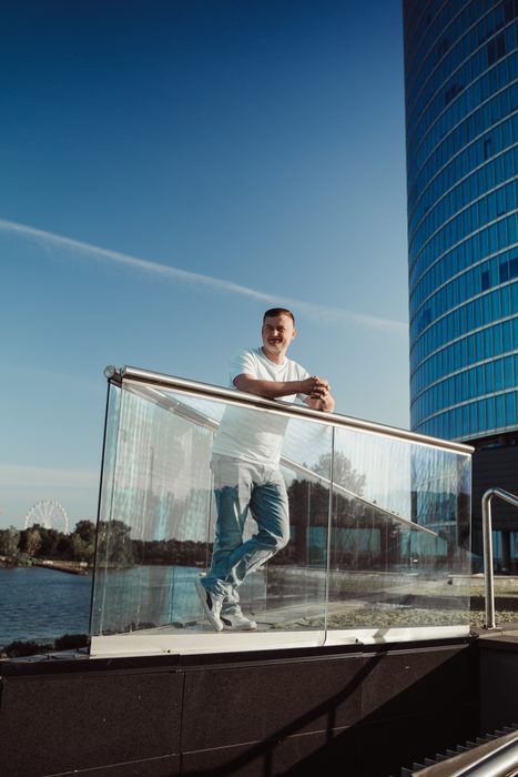 Vīrietis baltā kreklā un džinsos pilsētas portretā