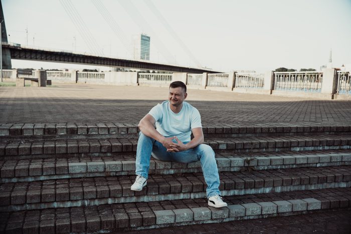Vīrietis baltā kreklā un džinsos pilsētas portretā