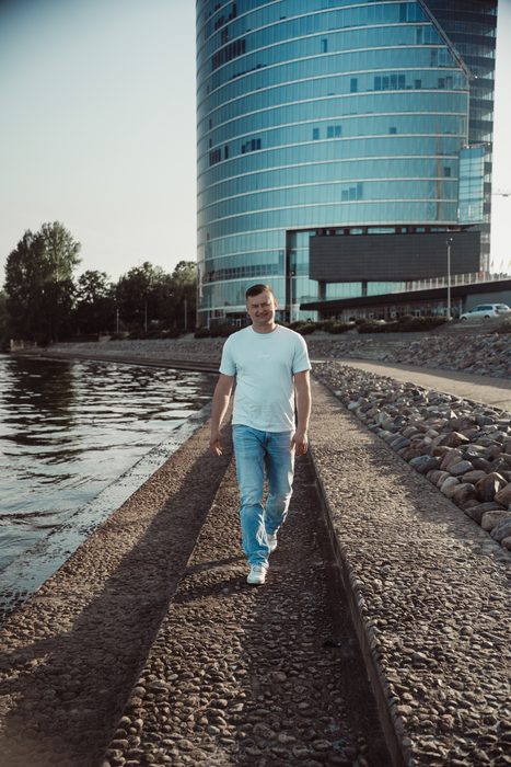 Vīrietis baltā kreklā un džinsos pilsētas portretā