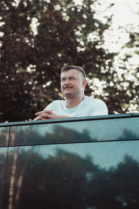 Vīrietis baltā kreklā un džinsos pilsētas portretā