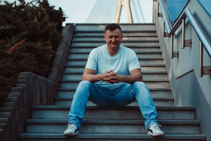Vīrietis baltā kreklā un džinsos pilsētas portretā