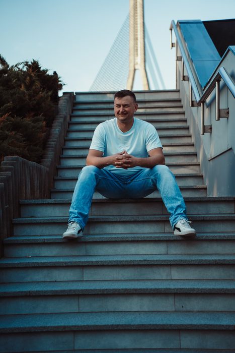 Vīrietis baltā kreklā un džinsos pilsētas portretā
