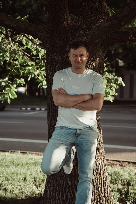 Vīrietis baltā kreklā un džinsos pilsētas portretā