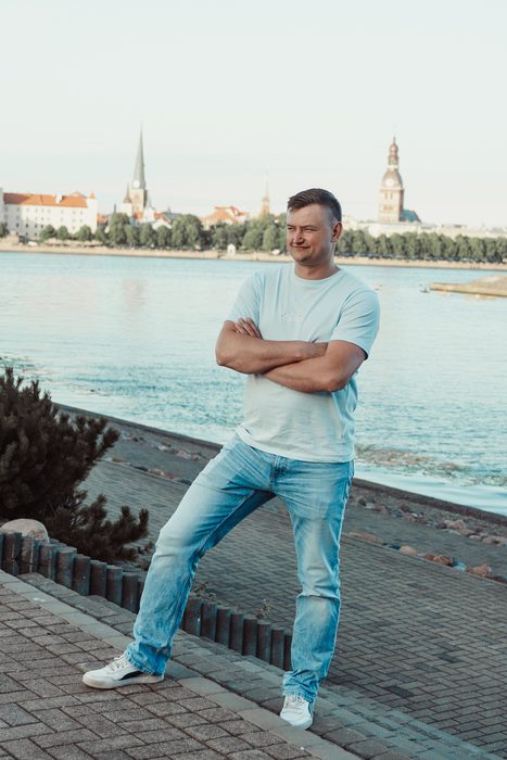 Vīrietis baltā kreklā un džinsos pilsētas portretā
