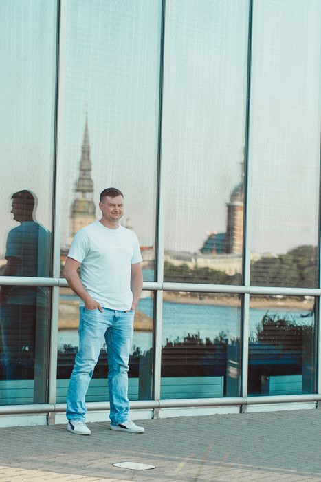Vīrietis baltā kreklā un džinsos pilsētas portretā