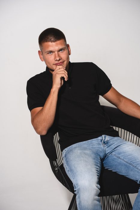 Vīrieša studijas portrets melnā polo kreklā