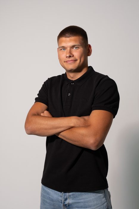 Studio portrait of a man in a black polo shirt and jeans