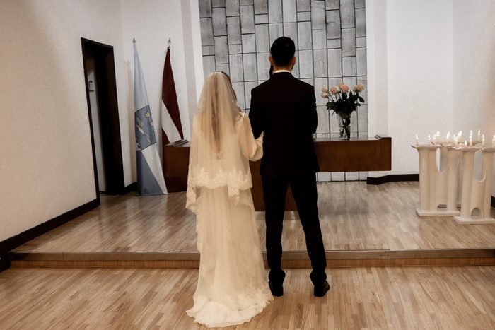 Couple at the altar during the wedding ceremony in Jūrmala, with the Latvian flag and candles