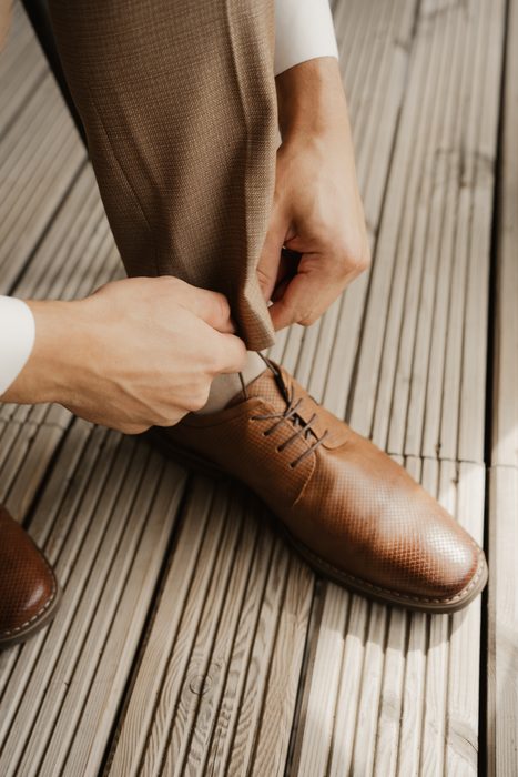 Groom tying a brown shoe