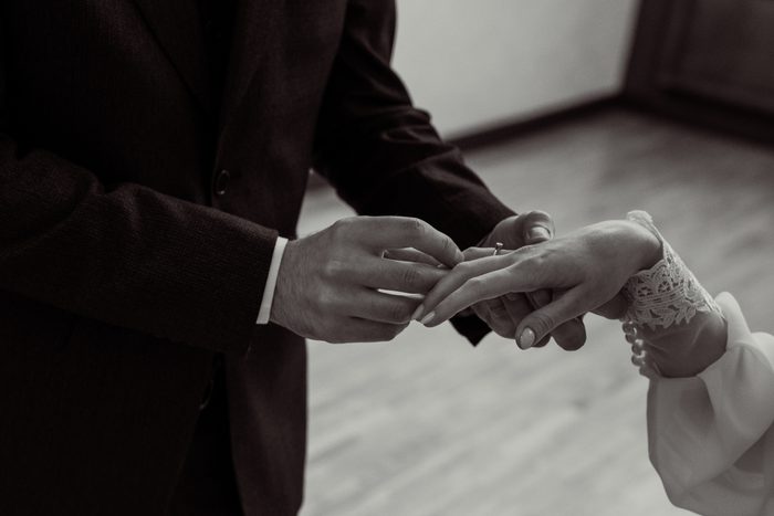 Black and white frame of the groom placing the wedding ring at the ceremony in Jūrmala