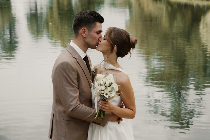 Newlywed portraits with a white bouquet beside the water