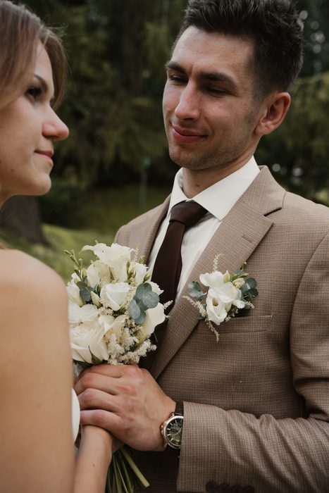Newlywed portraits with a white bouquet beside the water