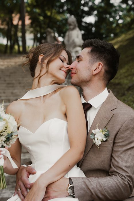 Newlyweds kissing beside the trees