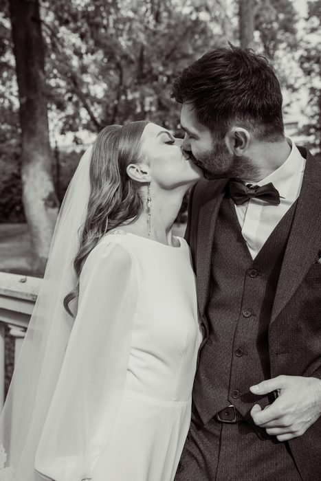 Black and white kiss by the park railing in Ķemeri