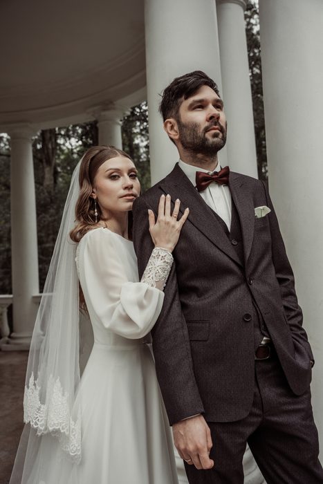 The bride with her hand on the groom's chest between the rotunda columns in Ķemeri