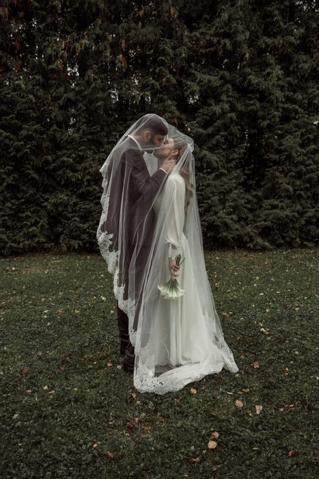 A kiss under the lace veil on the lawn in Ķemeri Park