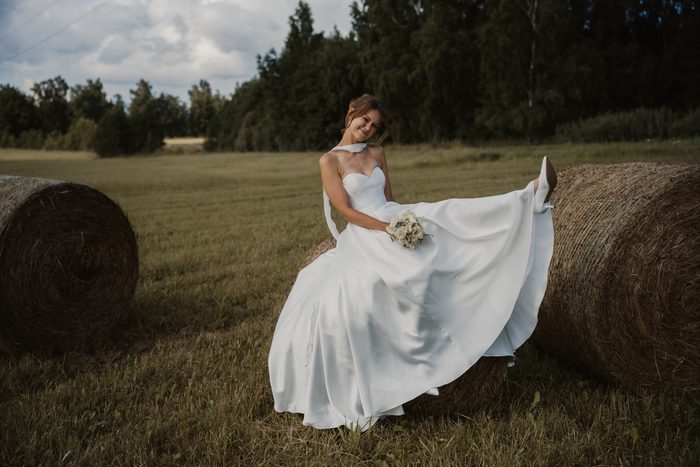 Bride in a white dress sitting on a hay bale