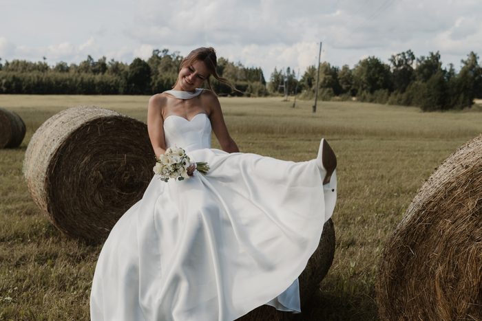 Bride in a white dress sitting on a hay bale