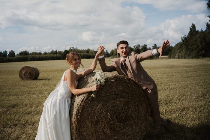 Newlyweds’ photoshoot in a field beside hay bales