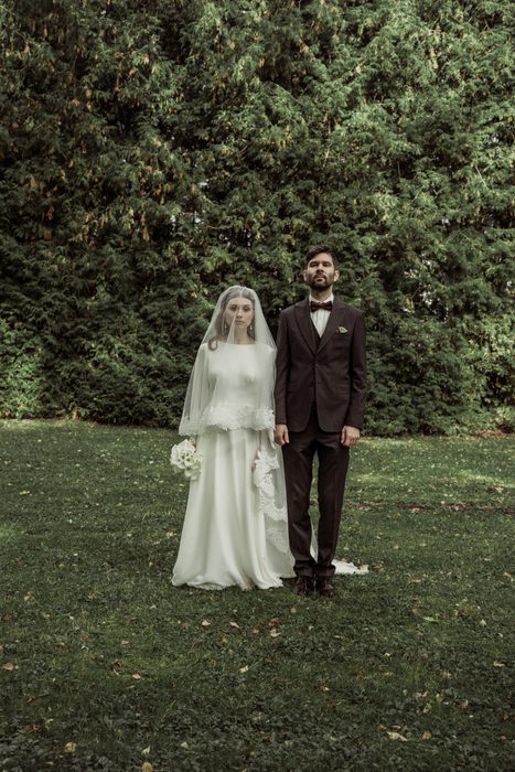 Full-length portrait of the couple in front of the yew hedge in Ķemeri Park