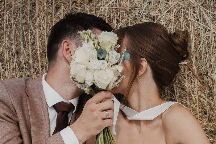 Newlyweds kissing behind a white flower bouquet