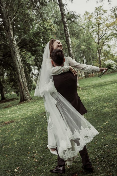 The groom lifting the laughing bride in Ķemeri Park