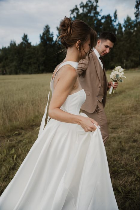 Newlyweds’ photoshoot in a field beside hay bales