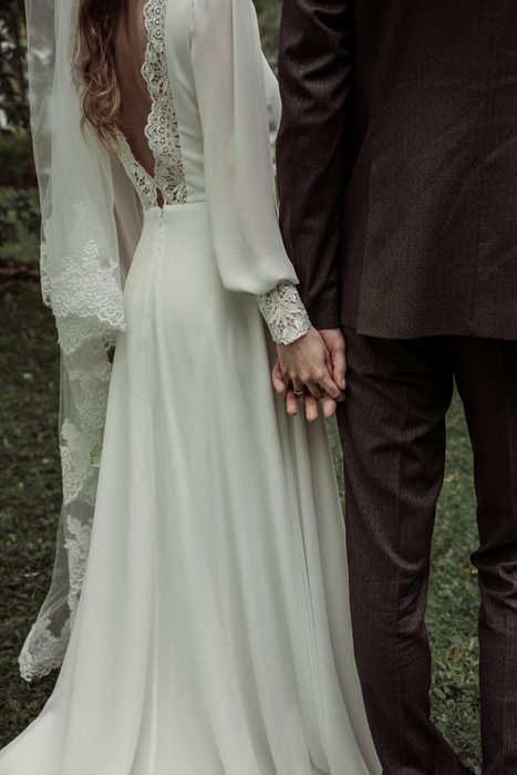 Close-up of the lace back of the dress and clasped hands in Ķemeri Park