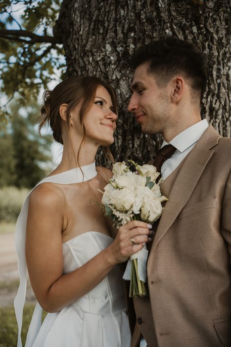 Newlyweds kissing beside the trees