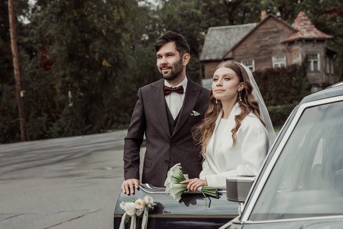 The couple beside a vintage car decorated with flowers on the Ķemeri outing