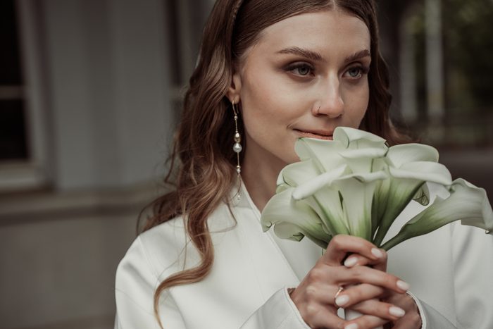 Portrait of the bride with a calla bouquet near her face in Ķemeri