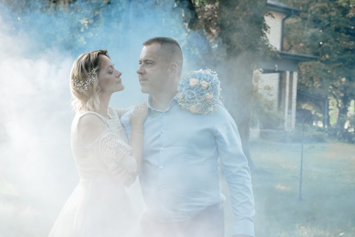 Wedding couple surrounded by blue smoke among trees