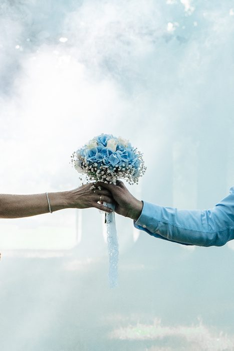 Wedding bouquet held out against a blue smoke background