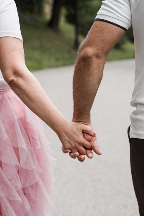 Couple holding hands on a walk through a park